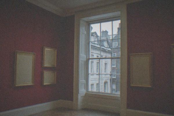 Grand gallery interior with portraits hanging in gilded frames along a wood-panelled wall