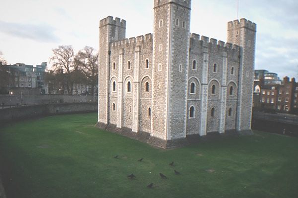 A stone fortress tower with green lawns and a historic wall walk